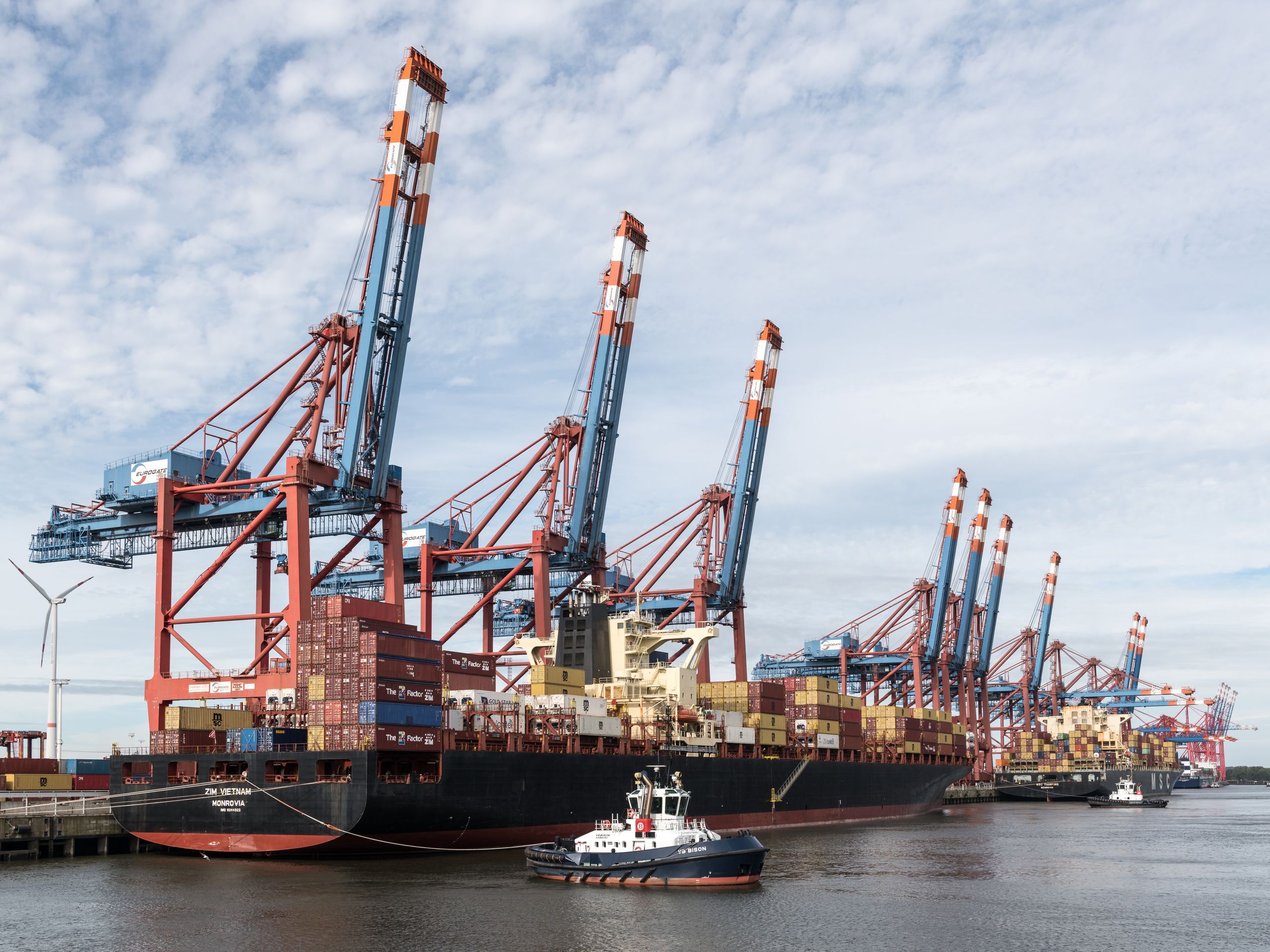Container ship docked at Port of Hamburg, cargo cranes visible.